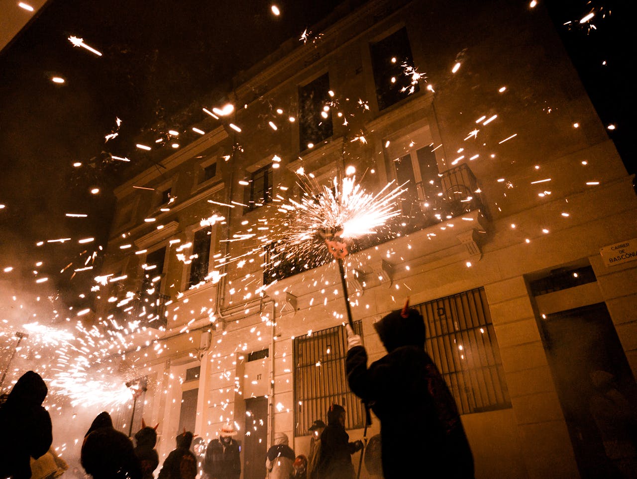 Dynamic scene of a street celebration with fireworks in Barcelona at night.
